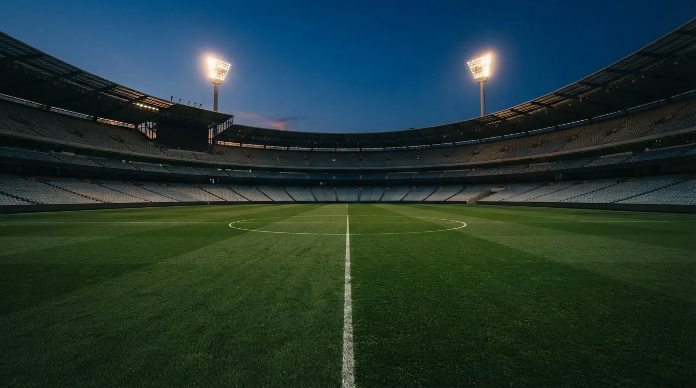 Een leeg voetbalstadion met lichtmasten bij schemering