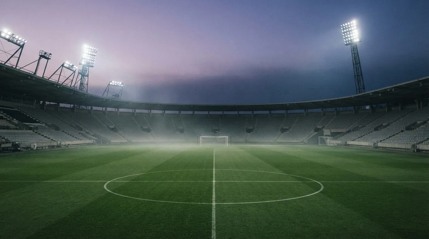 Een leeg voetbalstadion met lichtmasten bij schemering