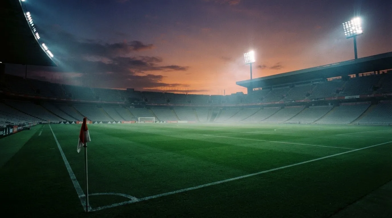 Een leeg voetbalstadion met lichtmasten bij schemering