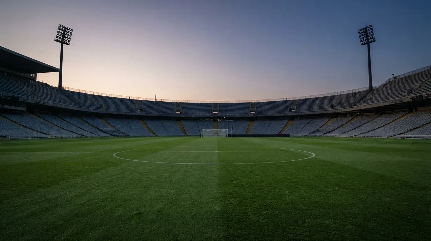 Een leeg voetbalstadion met lichtmasten bij schemering