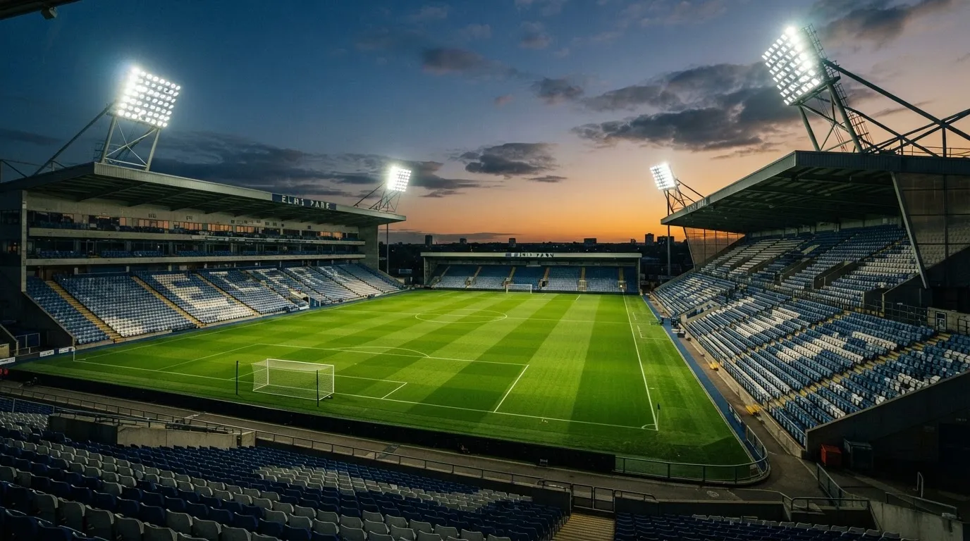 Een leeg voetbalstadion met lichtmasten bij schemering