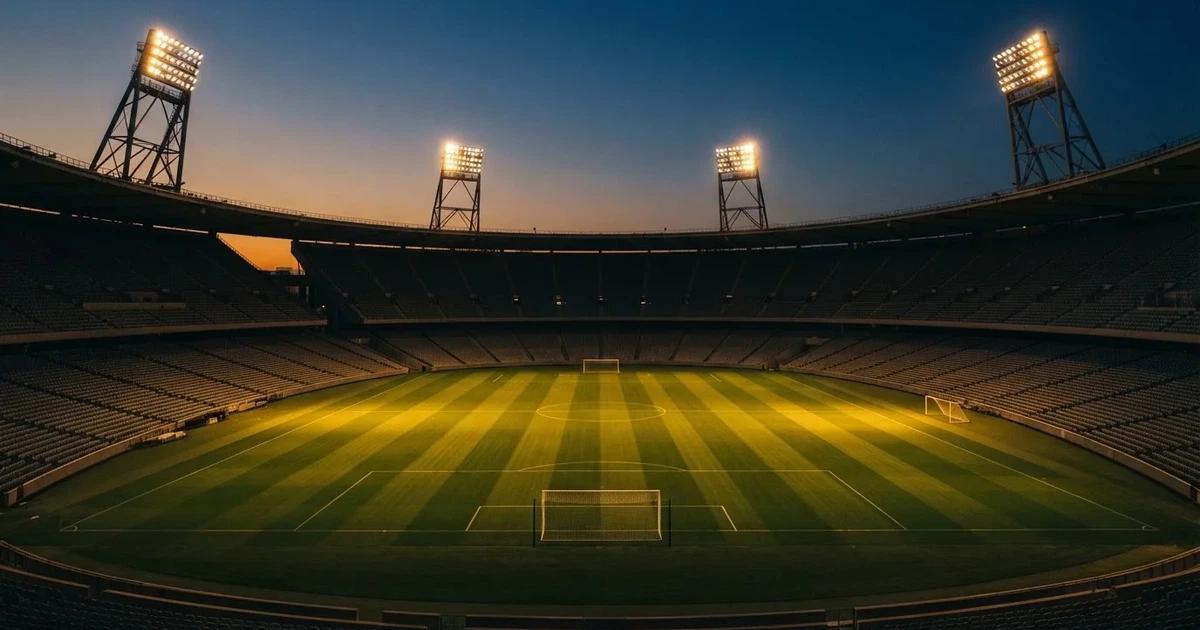 Een leeg voetbalstadion met lichtmasten bij schemering