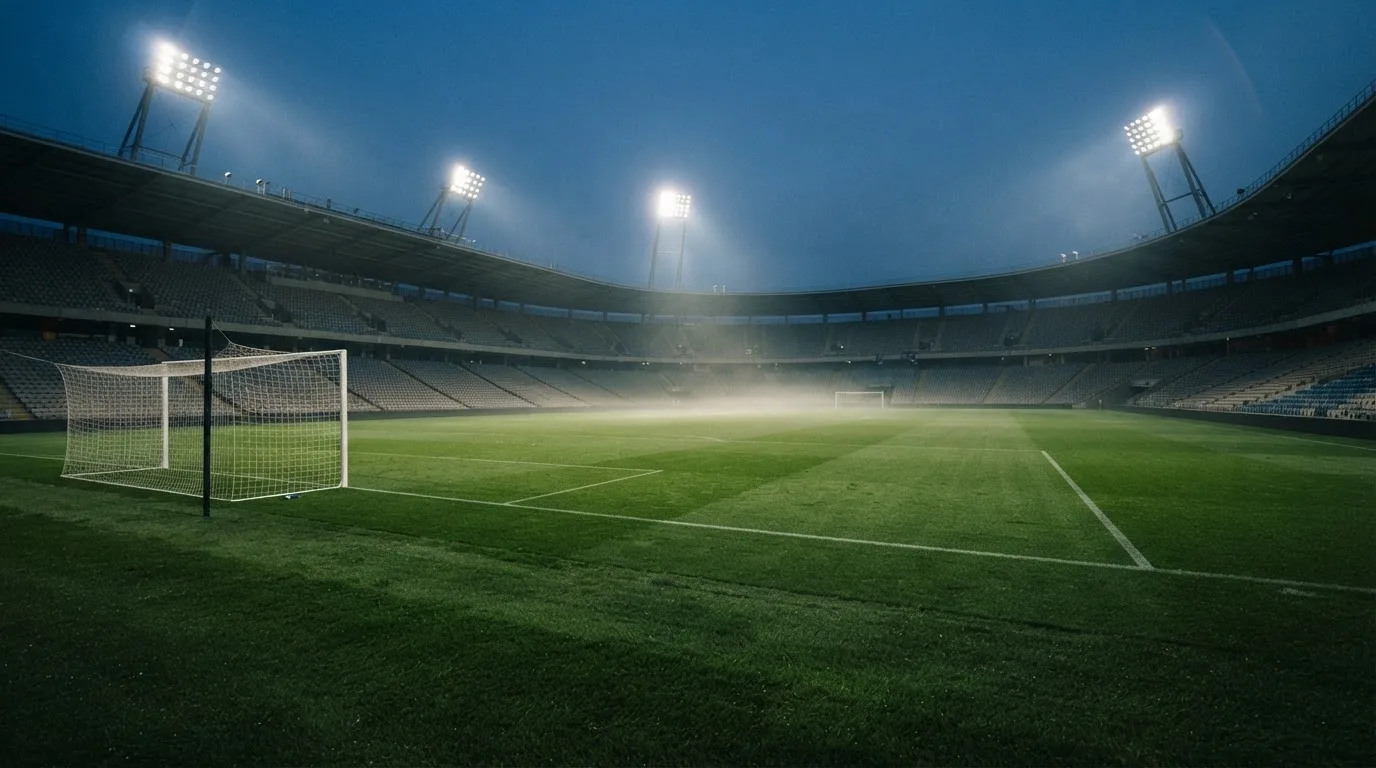 Een leeg voetbalstadion met lichtmasten bij schemering