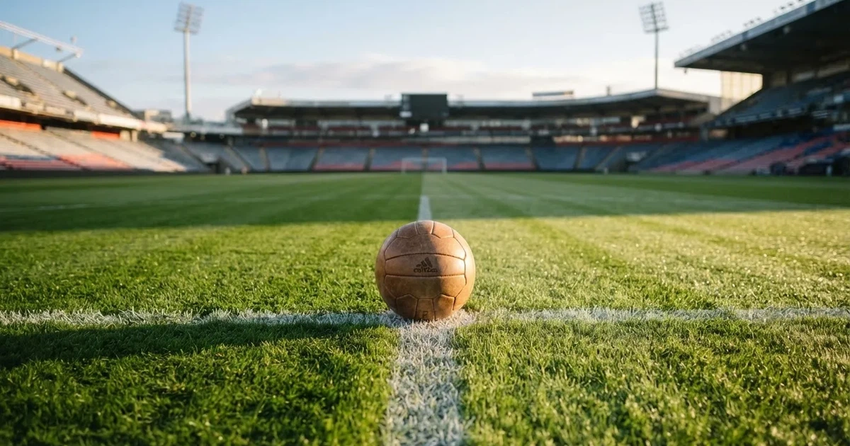 Een voetbal op de middenstip van een grasveld in het ochtendlicht