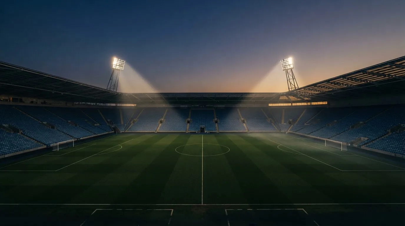Een leeg voetbalstadion met lichtmasten bij schemering