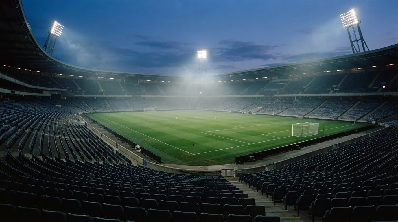 Een leeg voetbalstadion met lichtmasten bij schemering