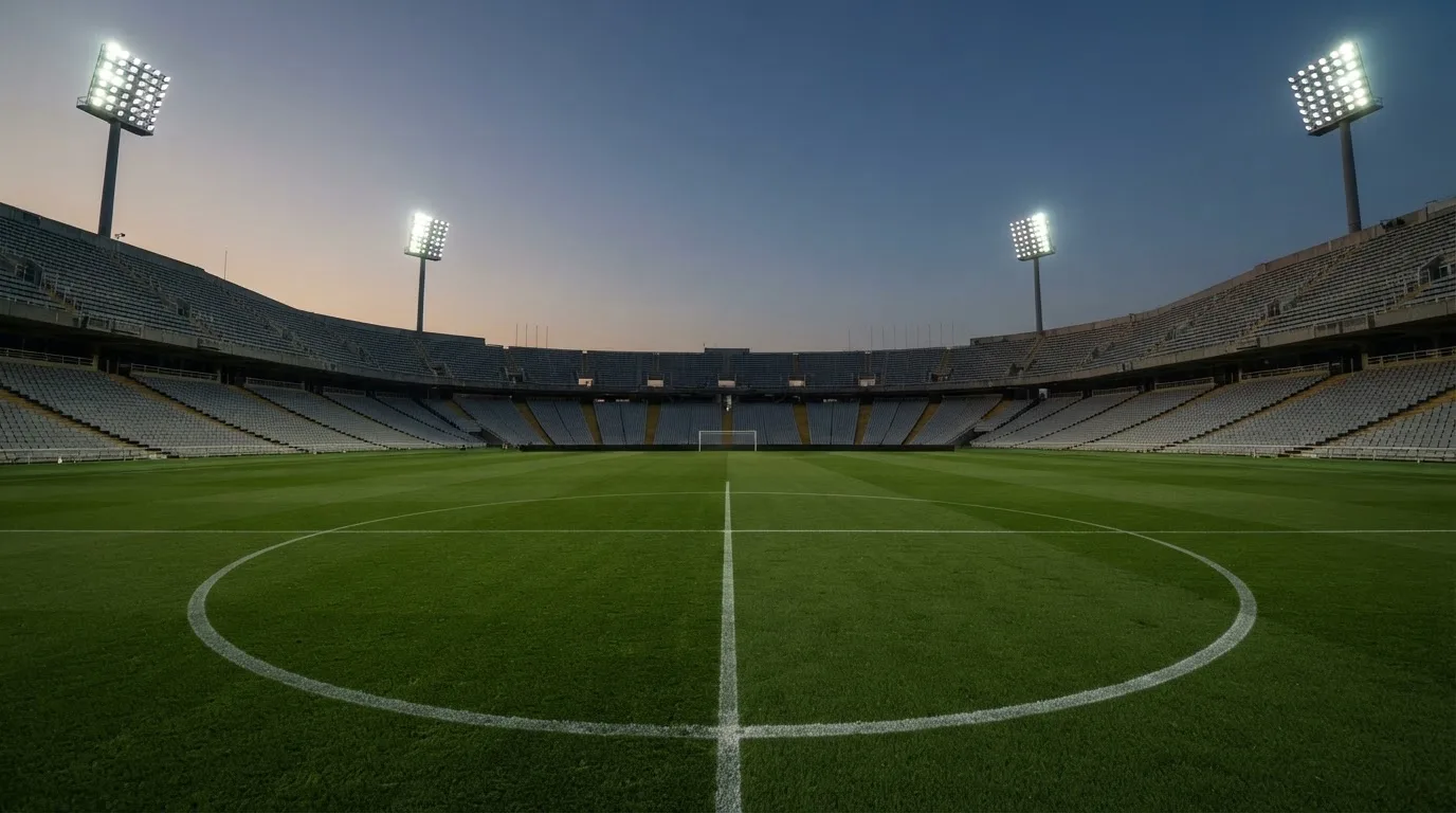 Een leeg voetbalstadion met lichtmasten bij schemering