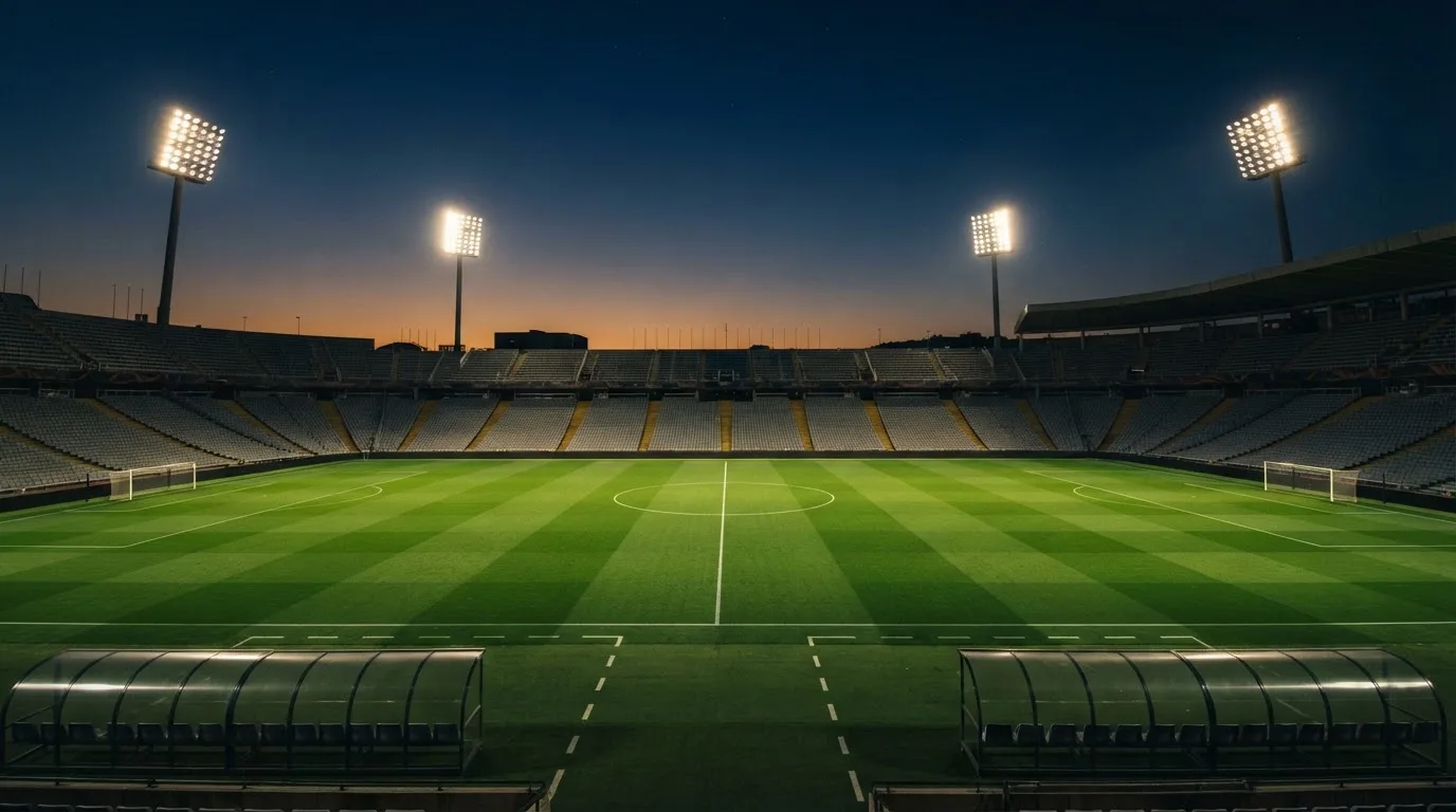 Een leeg voetbalstadion met lichtmasten bij schemering