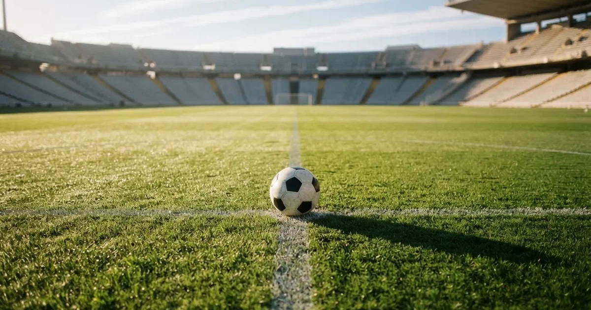 Een voetbal op de middenstip van een grasveld in het ochtendlicht
