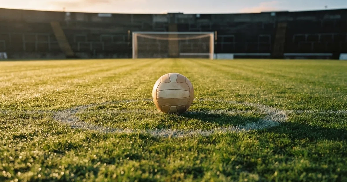 Een voetbal op de middenstip van een grasveld in het ochtendlicht