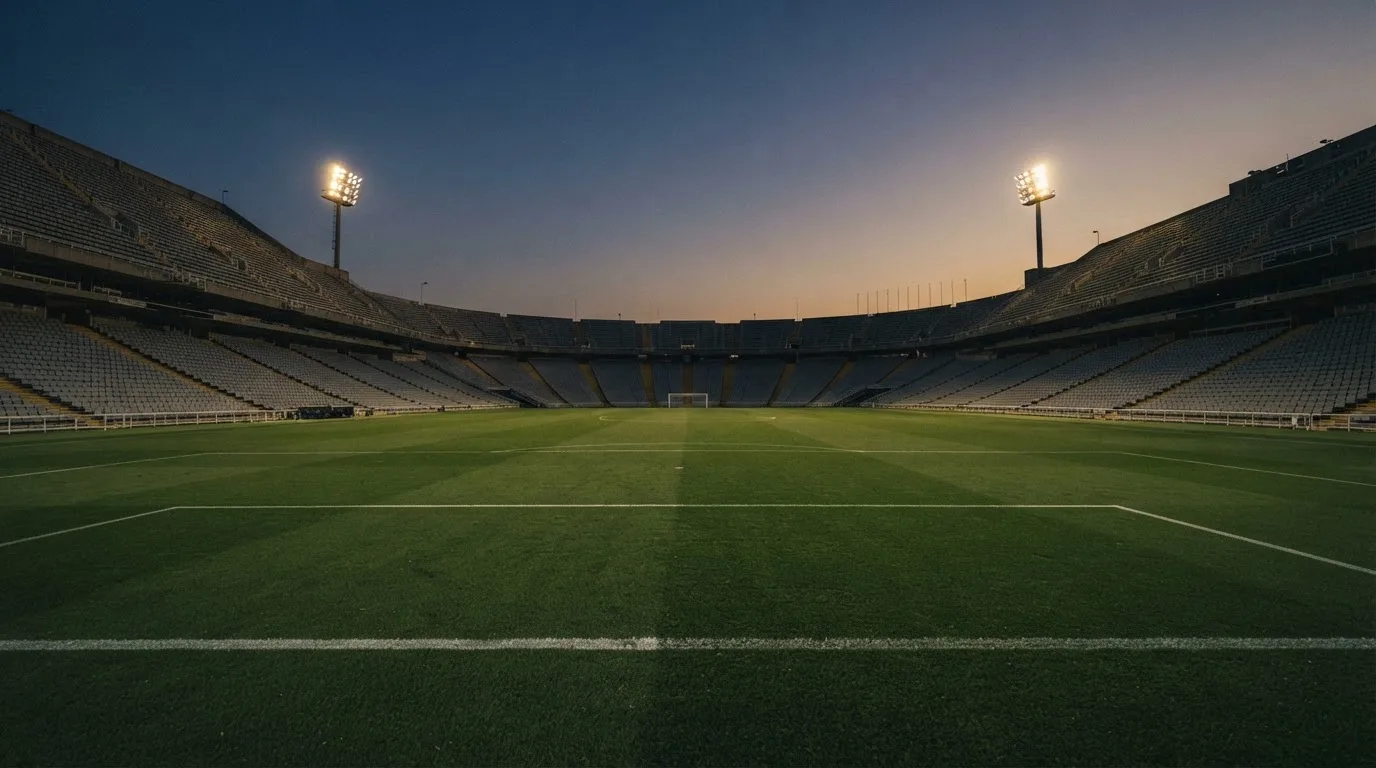 Een leeg voetbalstadion met lichtmasten bij schemering