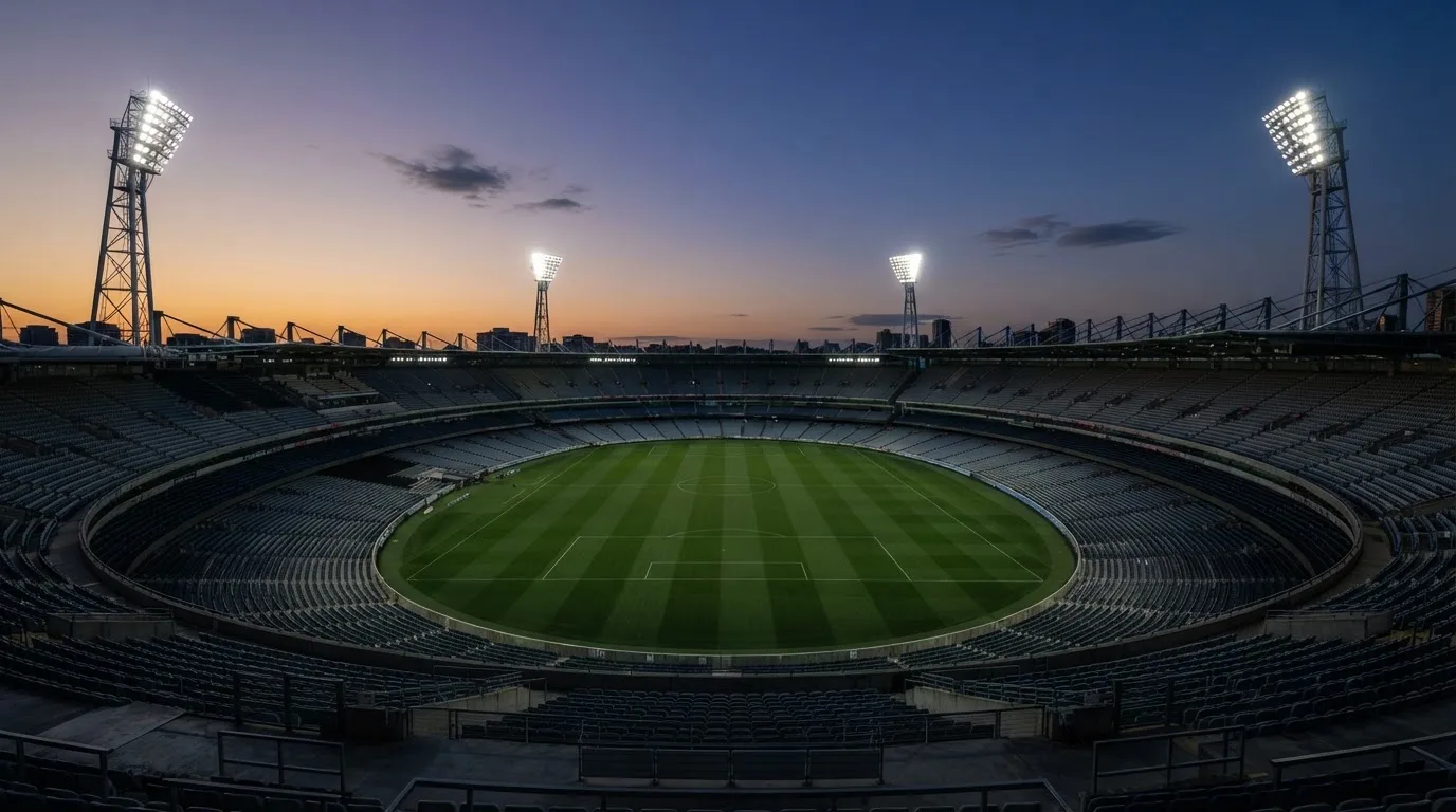 Een leeg voetbalstadion met lichtmasten bij schemering