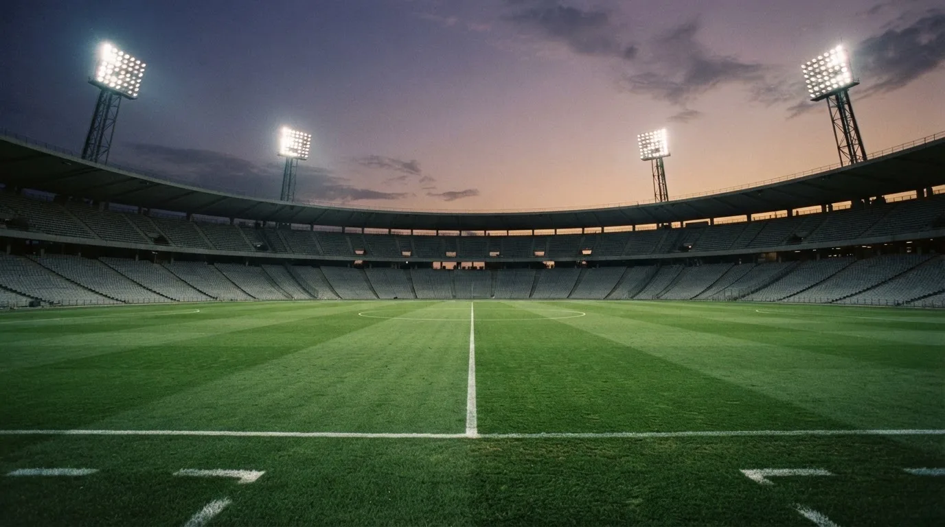 Een leeg voetbalstadion met lichtmasten bij schemering
