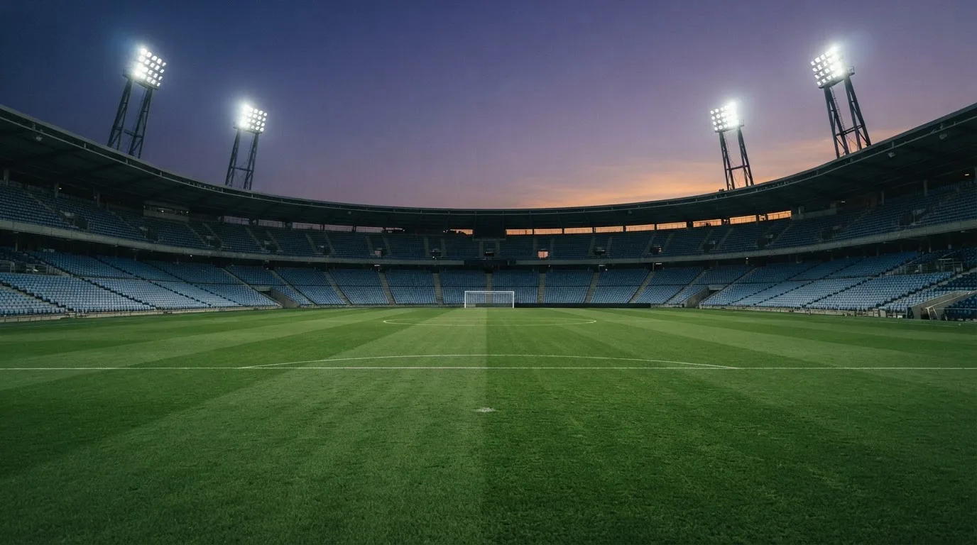 Een leeg voetbalstadion met lichtmasten bij schemering