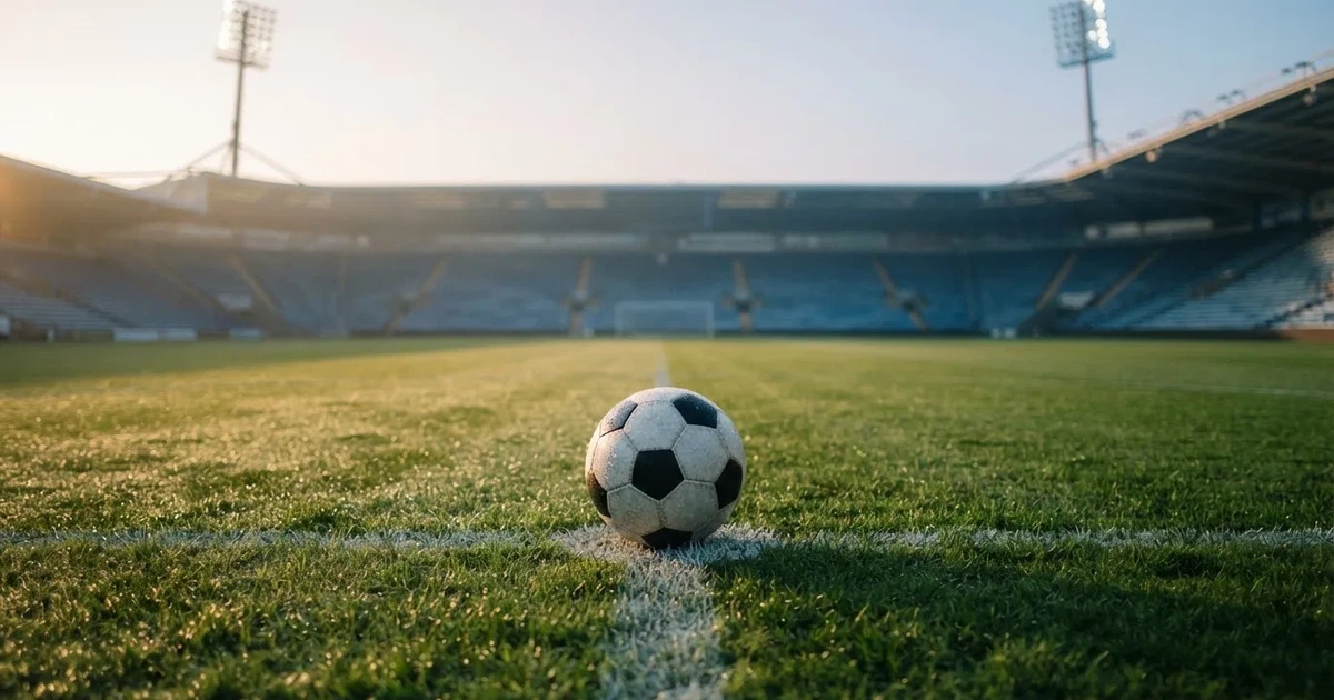 Een voetbal op de middenstip van een grasveld in het ochtendlicht