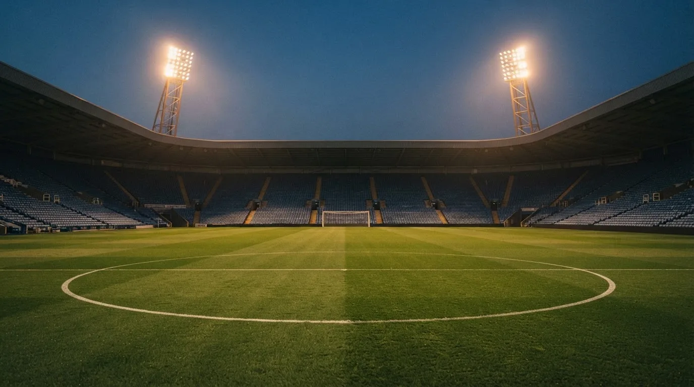 Een leeg voetbalstadion met lichtmasten bij schemering
